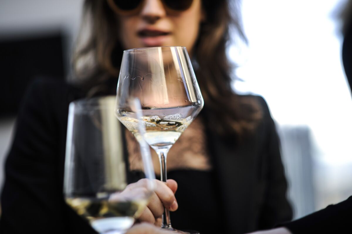 Women clink wine glasses at an event.