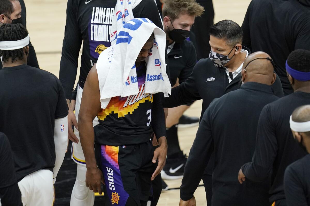 Suns guard Chris Paul (3) walks off the court with a towel over his head after injuring his right shoulder.