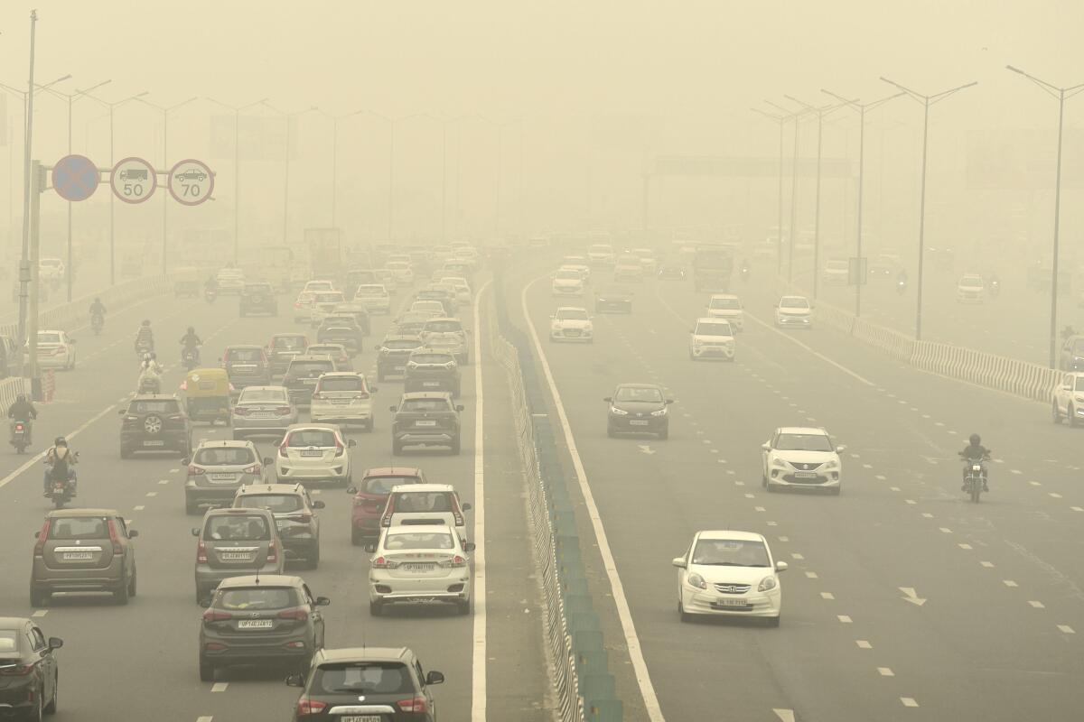 Autos y motocicletas circulan por una carretera envuelta en smog en Nueva Delhi, India,