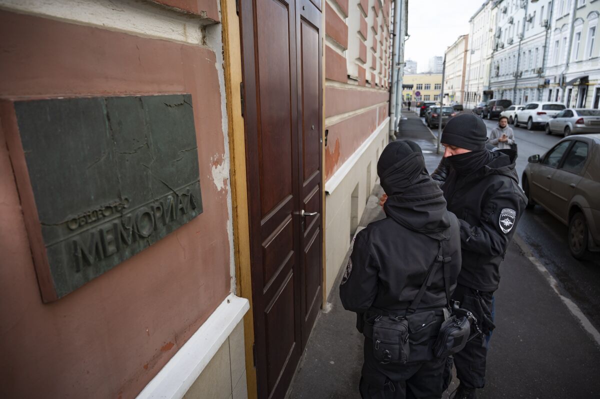 Two Russian police officers stand in front the door of the Memorial office in Moscow, Russia, Tuesday, March 21, 2023. The Russian authorities on Tuesday raided homes and offices of multiple human rights advocates and historians with the prominent rights group Memorial that won the Nobel Peace Prize last year. (AP Photo)