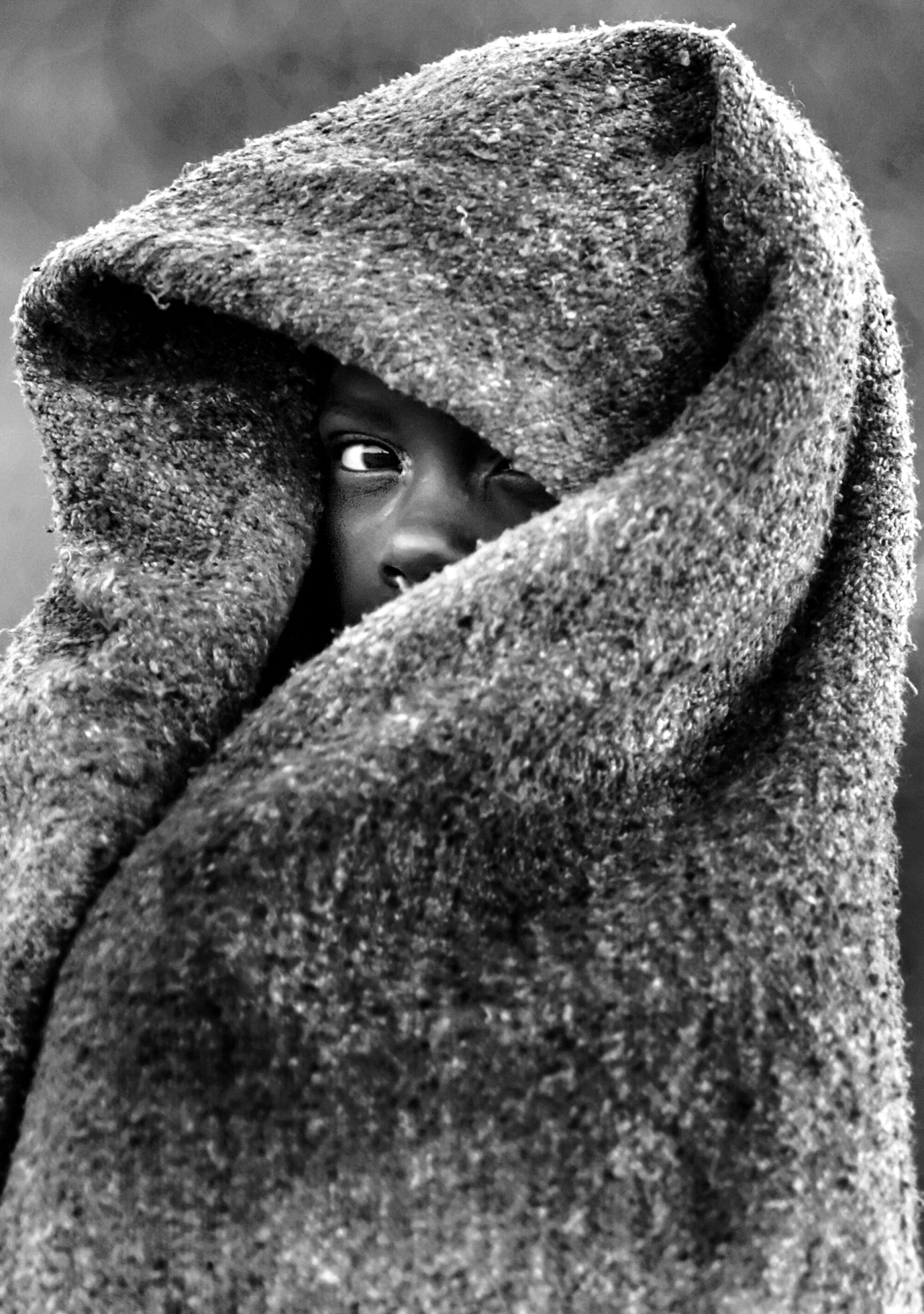 A child wrapped in a blanket; only part of their face is visible