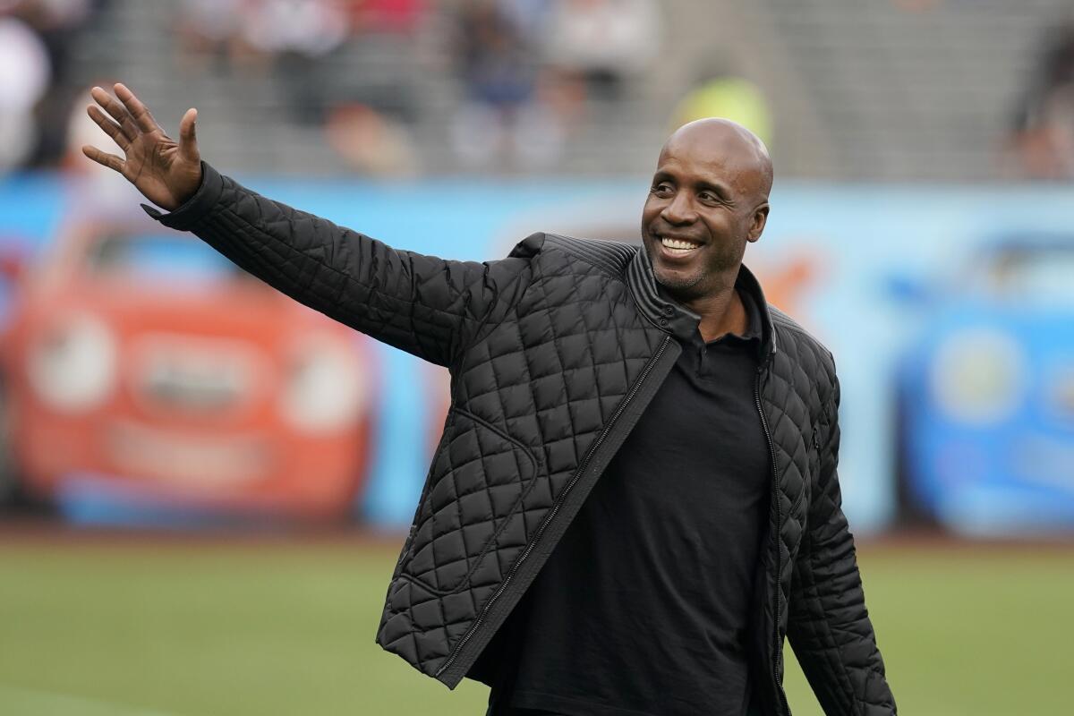 Barry Bonds, in a black jacket, waves  to the crowd