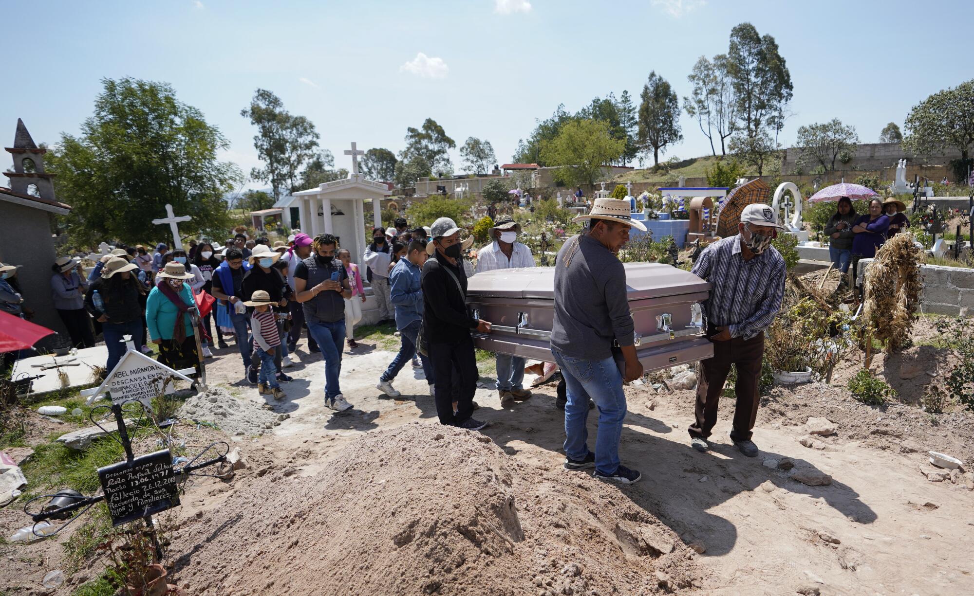 The casket of Maria Eugenia Chavez Segovia is carried to its grave site at Tultepec Cemetery.