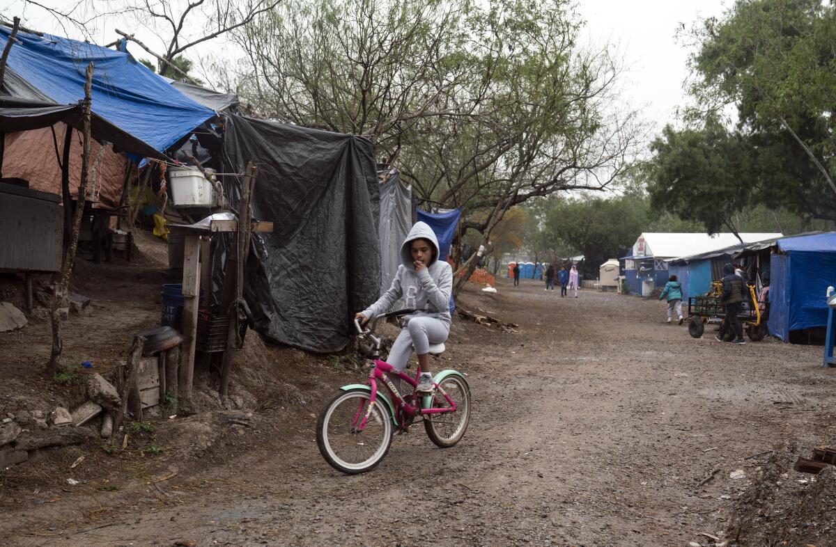 A girl rides her bike in a migrant camp in Matamoros, Mexico.