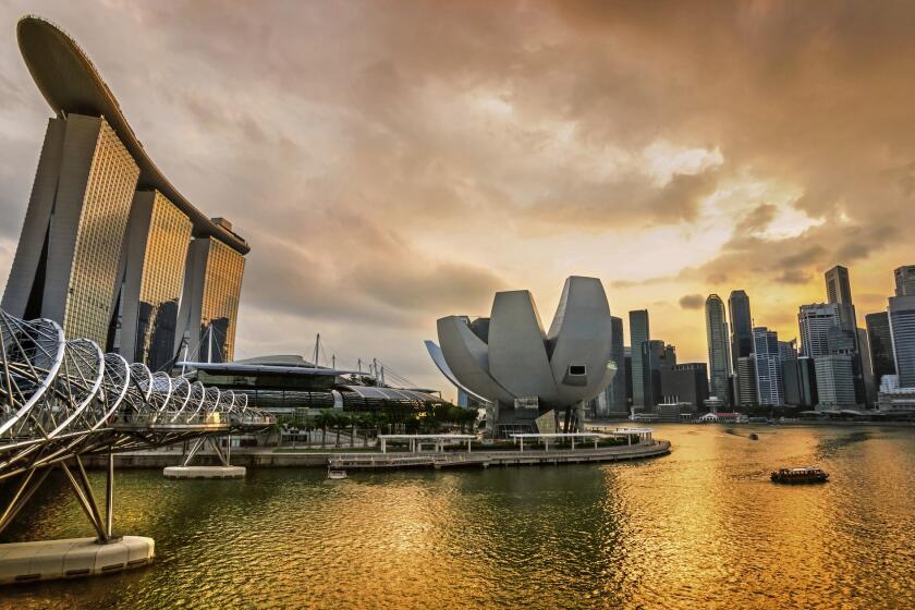 The dramatic Singapore city skyline at sunset, with the striking Marina Bay Sands Hotel to the left, three towers with a Skypark atop them. On Aug. 9, 2015, Singapore celebrates its golden jubilee.