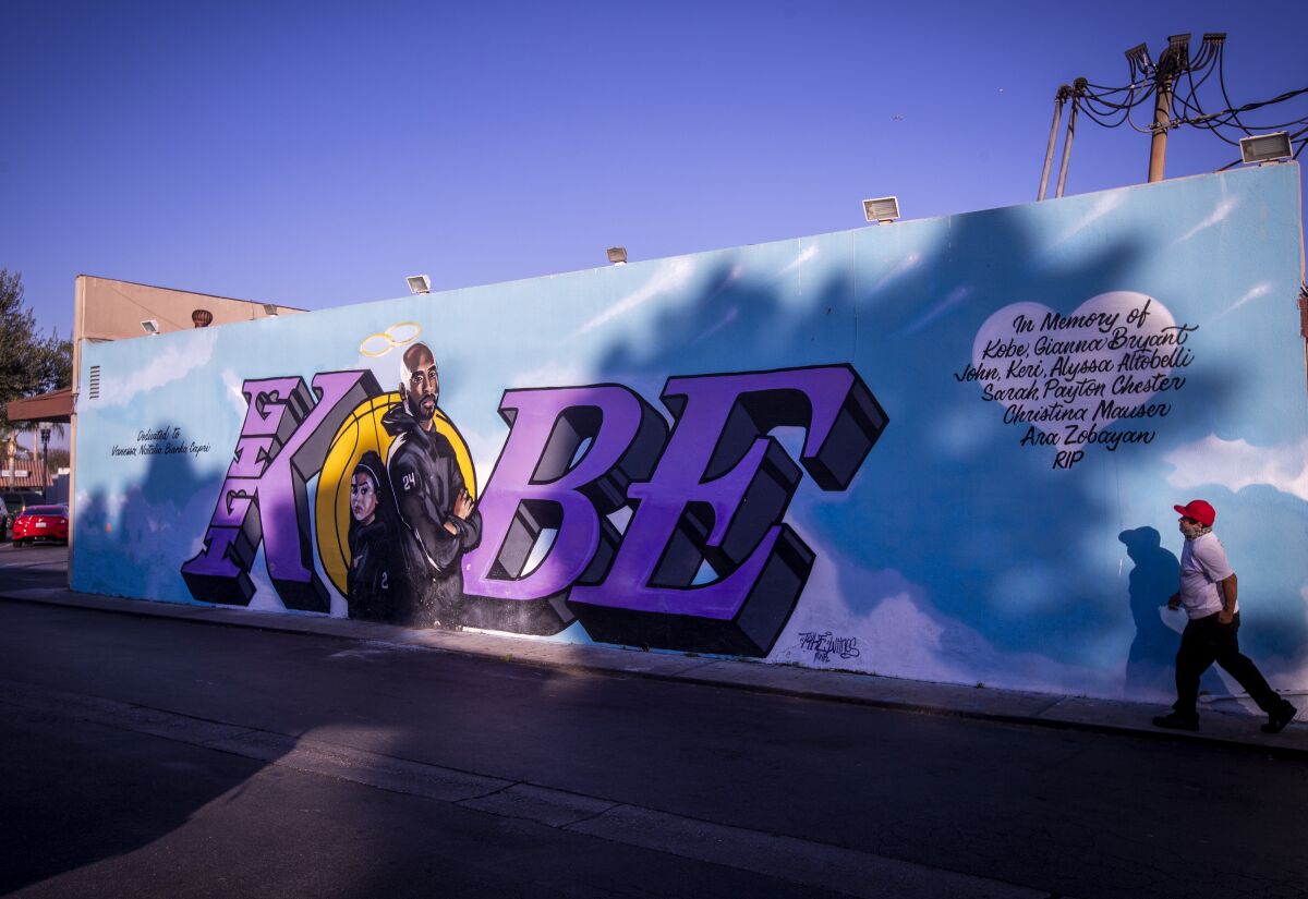 A person views a blue and purple Kobe and Gianna Bryant mural