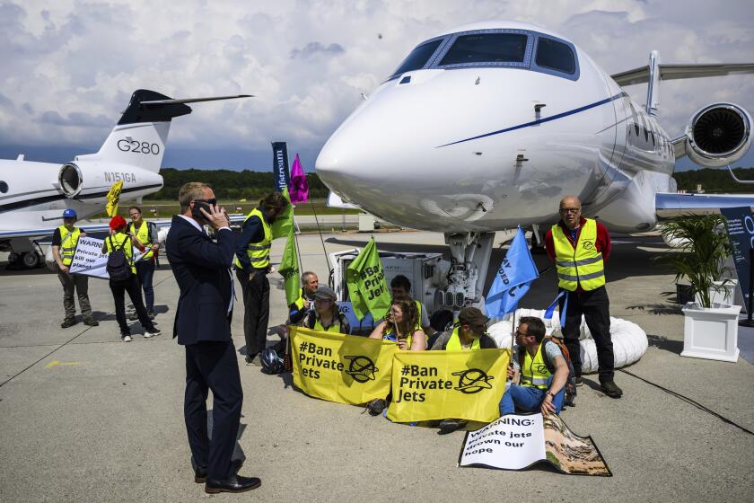 ARCHIVO - Activistas ambientales de la organización Greenpeace y de la red global Stay Grounded se manifiestan mientras están esposados a un avión durante la Convención y Exposición Europea de Aviación Comercial, el 23 de mayo de 2023, en el aeropuerto de Ginebra, Suiza. (Laurent Gillieron/Keystone vía AP, archivo)