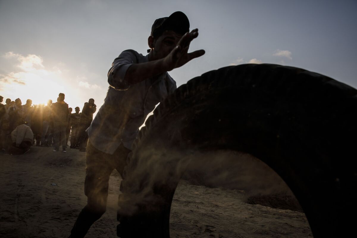 A demonstrator rolls a tire to the front of the border protest in Bureij, near Deir al Balah in the Gaza Strip on Tuesday.