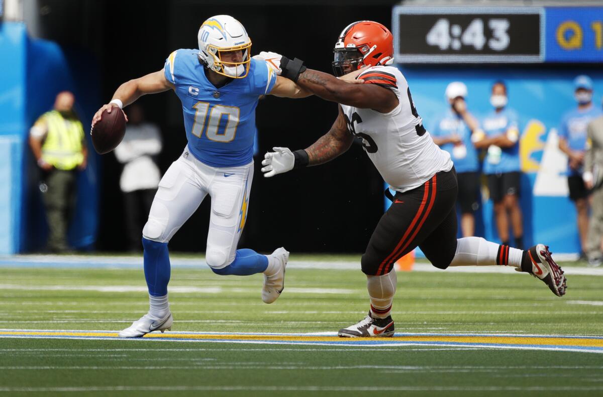Chargers quarterback Justin Herbert tries to evade Cleveland Browns defensive tackle Jordan Elliott.