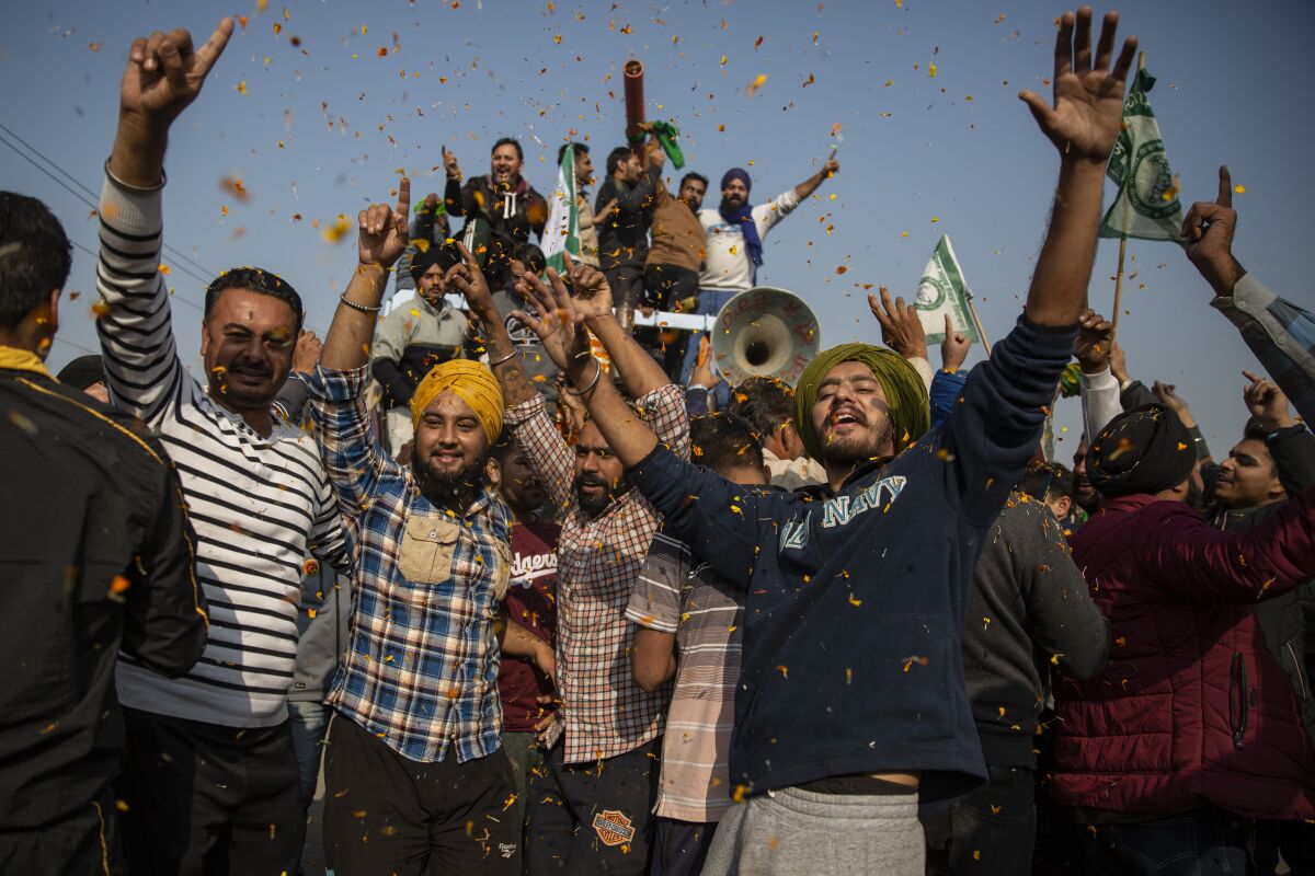 Indian farmers are showered with flower petals as they dance while leaving the protest site in Singhu, on the outskirts of New Delhi, India, Saturday, Dec. 11, 2021. Tens of thousands of jubilant Indian farmers on Saturday cleared protest sites on the capital’s outskirts and began returning home, marking an end to their year-long demonstrations against agricultural reforms that were repealed by Prime Minister Narendra Modi's government in a rare retreat. (AP Photo/Altaf Qadri)