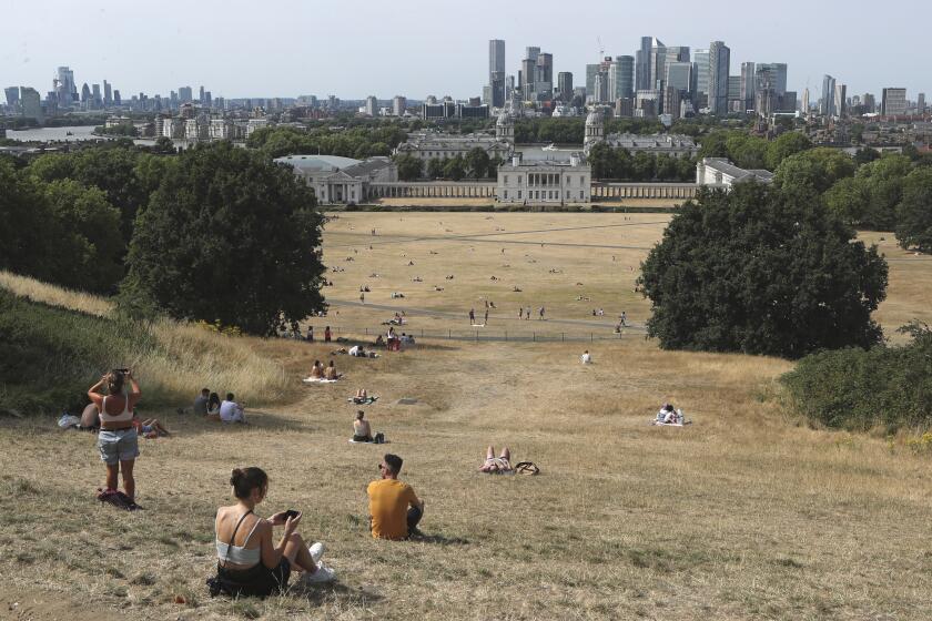 FILE - People sit on the sun-parched grass in Greenwich Park with the Maritime museum and Canary Wharf financial district in the background in London, Sunday July 17, 2022. Britain had its warmest year on record in 2022, official figures showed Thursday, Jan. 5, 2023, the latest evidence of how climate change is transforming Europe’s weather. (AP Photo/Tony Hicks, File)
