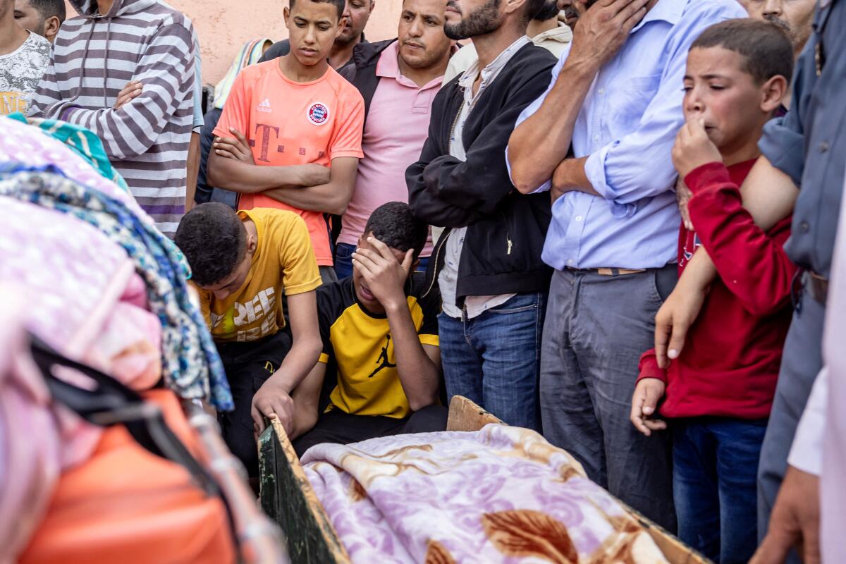 People stand near one another while mourning an earthquake victim.