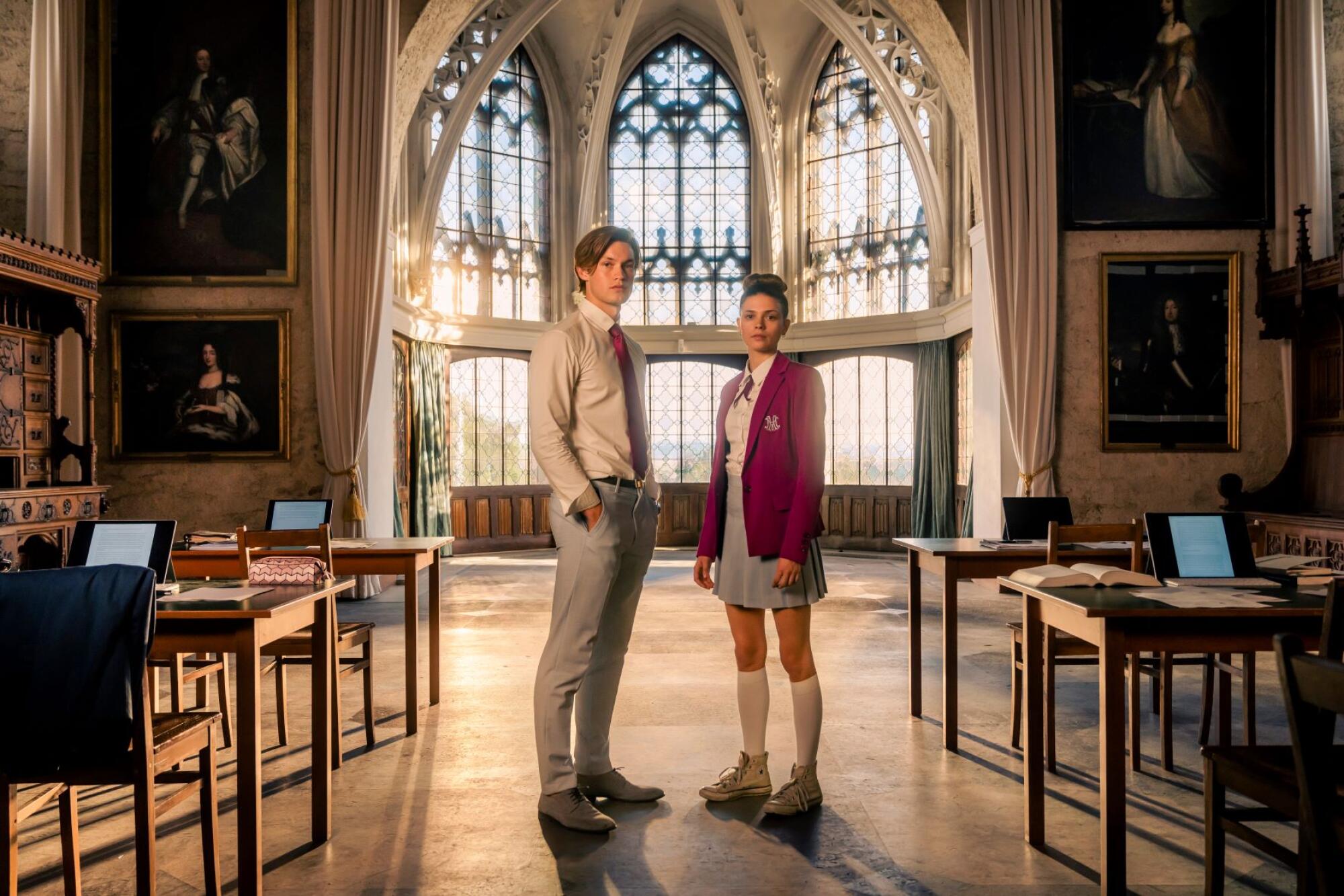 A man and a woman stand in front of a stained glass window in "Maxton Hall — the World Between Us."