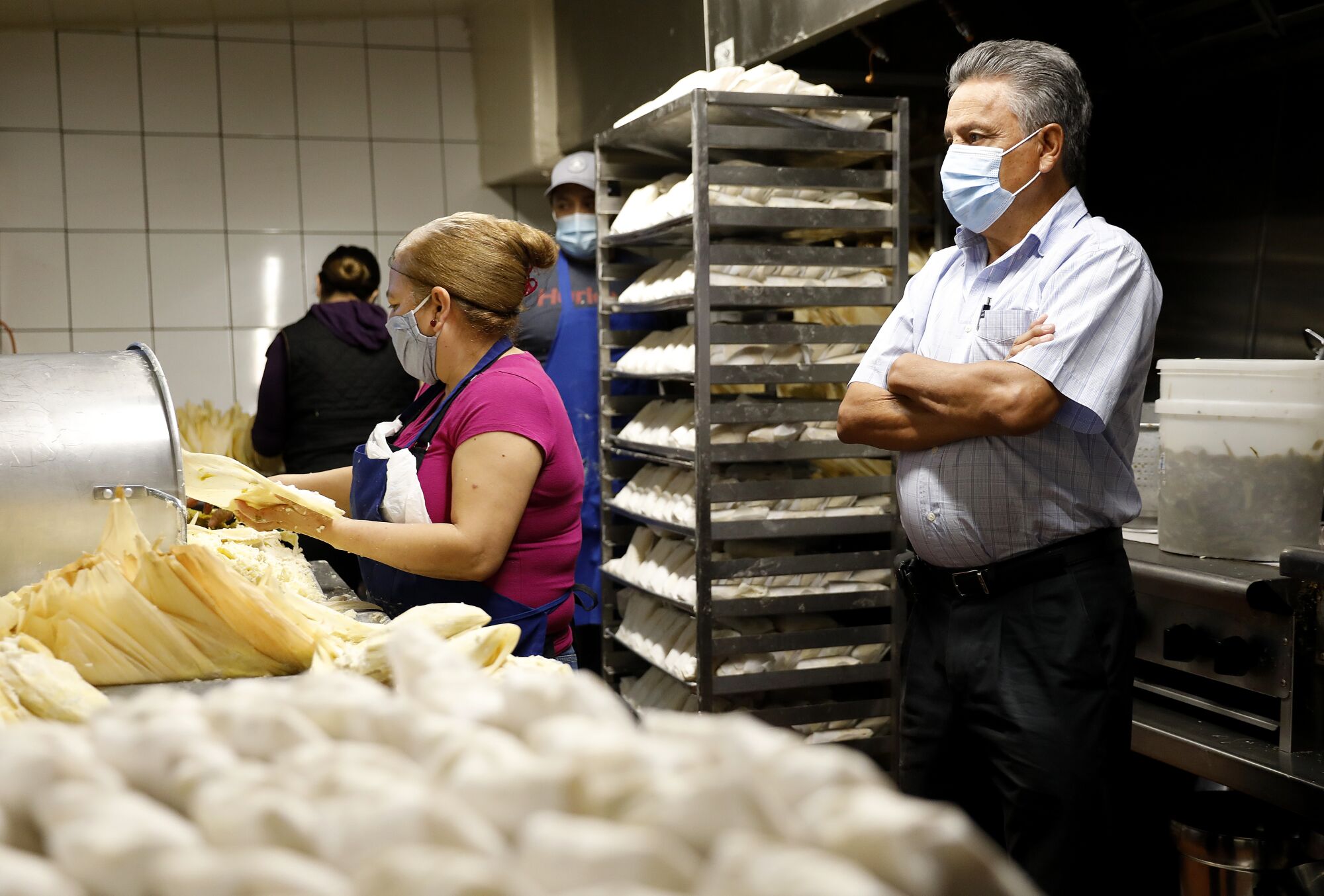 Juan Manuel Santoyo looks on as workers including Maria Franco make tamales at Tamales Liliana's