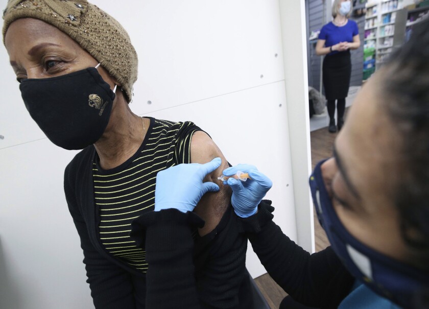 Pharmacist Asha Fowells vaccinates Judy Phillips, aged 75, with her first dose of the Oxford AstraZeneca coronavirus vaccine, at Copes Pharmacy and Travel Clinic in Streatham, south London, Thursday, Feb. 4, 2021. (Yui Mok/PA via AP)
