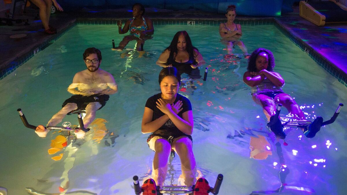 Aqua cycling class participants do crunches in the pool by locking their feet under the handle bars of their bikes.