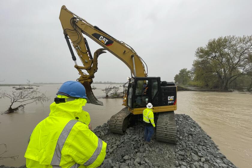 A crew works at repairing a levee rupture at the Pajaro River in Monterey County, Calif., Tuesday, March 14, 2023. Forecasters warned of more flooding, potentially damaging winds and difficult travel conditions on mountain highways as a new atmospheric river pushed into swamped California early Tuesday. (AP Photo/Haven Daley)