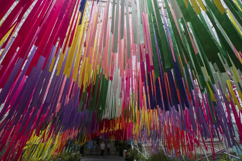 People walk under colorful ribbons at a same sex charity event in Bangkok, Thursday, July 9 , 2020. Thailand's Cabinet has approved two draft bills that would give same-sex unions legal status similar to that of heterosexual marriages. (AP Photo/Sakchai Lalit)