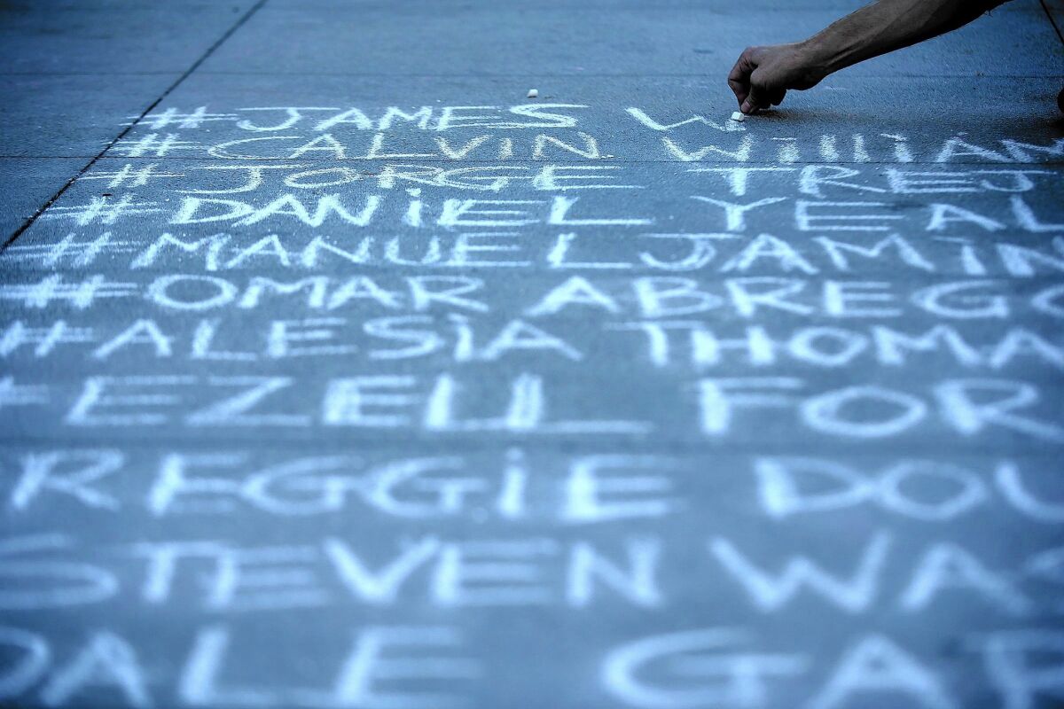 The names of people that protesters say were killed by Los Angeles police officers are written in chalk outside LAPD headquarters during a demonstration Tuesday.