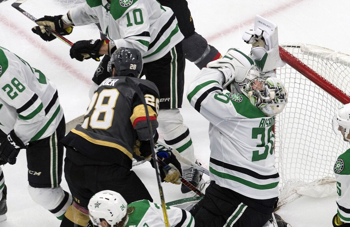 Dallas Stars goalie Ben Bishop (30) is hit by Vegas Golden Knights' William Carrier (28) during the third period of an NHL hockey playoff game Monday, Aug. 3, 2020, in Edmonton, Alberta. (Jason Franson/The Canadian Press via AP)