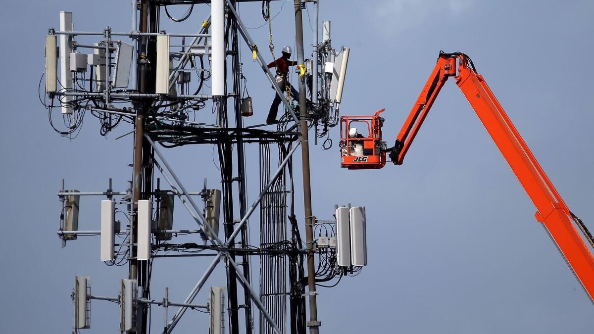 A worker climbs on a cellular communications tower in Oakland in 2014.