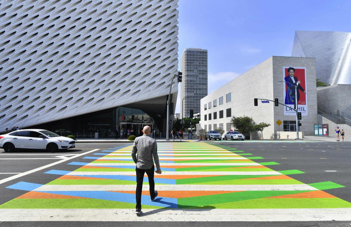 A pedestrian crosses the street toward the Broad Museum.