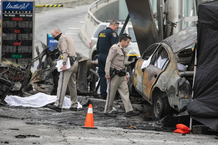 CHP officials walk around a scene of incinerated wrecked cars