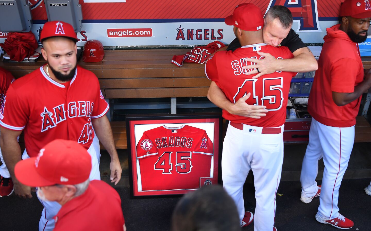 Angels Albert Pujols is hugged by an unidentified Anaheim police officer next to a framed jersey of Tyler Skaggs who was memorialized before a game with the Seattle Mariners.