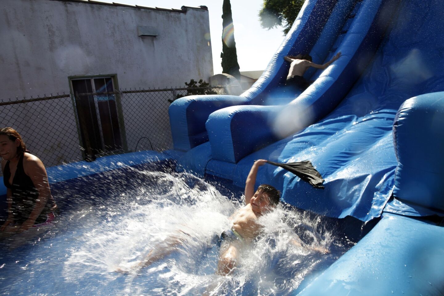 Children in Boyle Heights cool down in a 30-foot blow-up swimming pool at a birthday party on Sunday.