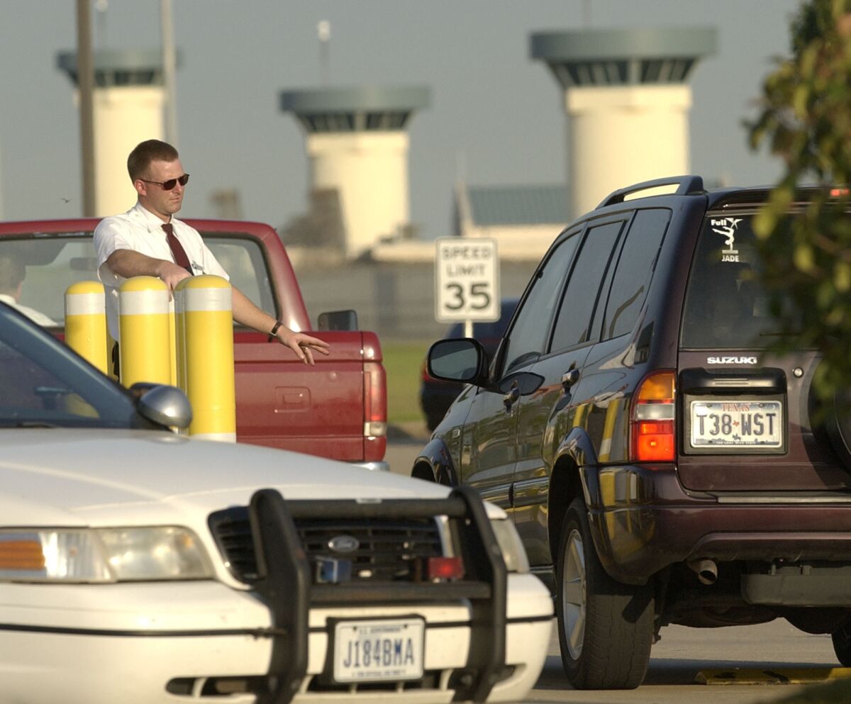 FILE - Vehicles are checked as they enter the Federal Bureau of Prisons complex, Wednesday, June 2, 2004 in Beaumont, Texas.Seven inmates have been charged with killing two fellow prisoners and wounding two others during a January, 2022 attack the a federal prison in Texas that led to a nationwide lockdown of the federal prison system a 15-count indictment filed this week said. (AP Photo/David J. Phillip)