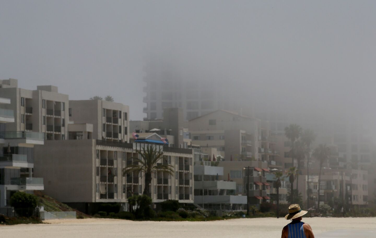 A man walks along the sand in Long Beach on Thursday morning as sun breaks through the marine layer.