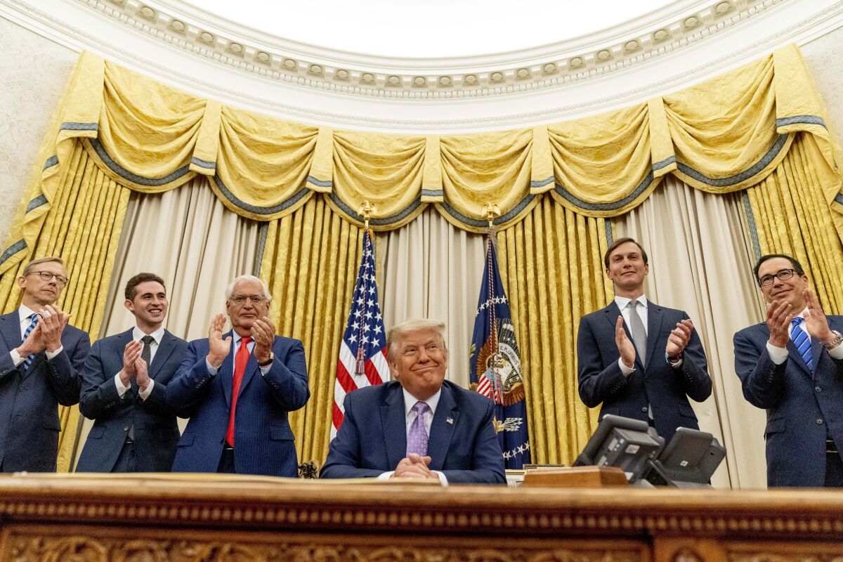 President Donald Trump, accompanied by From left, U.S. special envoy for Iran Brian Hook, Avraham Berkowitz, Assistant to the President and Special Representative for International Negotiations, U.S. Ambassador to Israel David Friedman, President Donald Trump's White House senior adviser Jared Kushner, and Treasury Secretary Steven Mnuchin, smiles in the Oval Office at the White House, Wednesday, Aug. 12, 2020, in Washington. Trump said on Thursday that the United Arab Emirates and Israel have agreed to establish full diplomatic ties as part of a deal to halt the annexation of occupied land sought by the Palestinians for their future state. (AP Photo/Andrew Harnik)