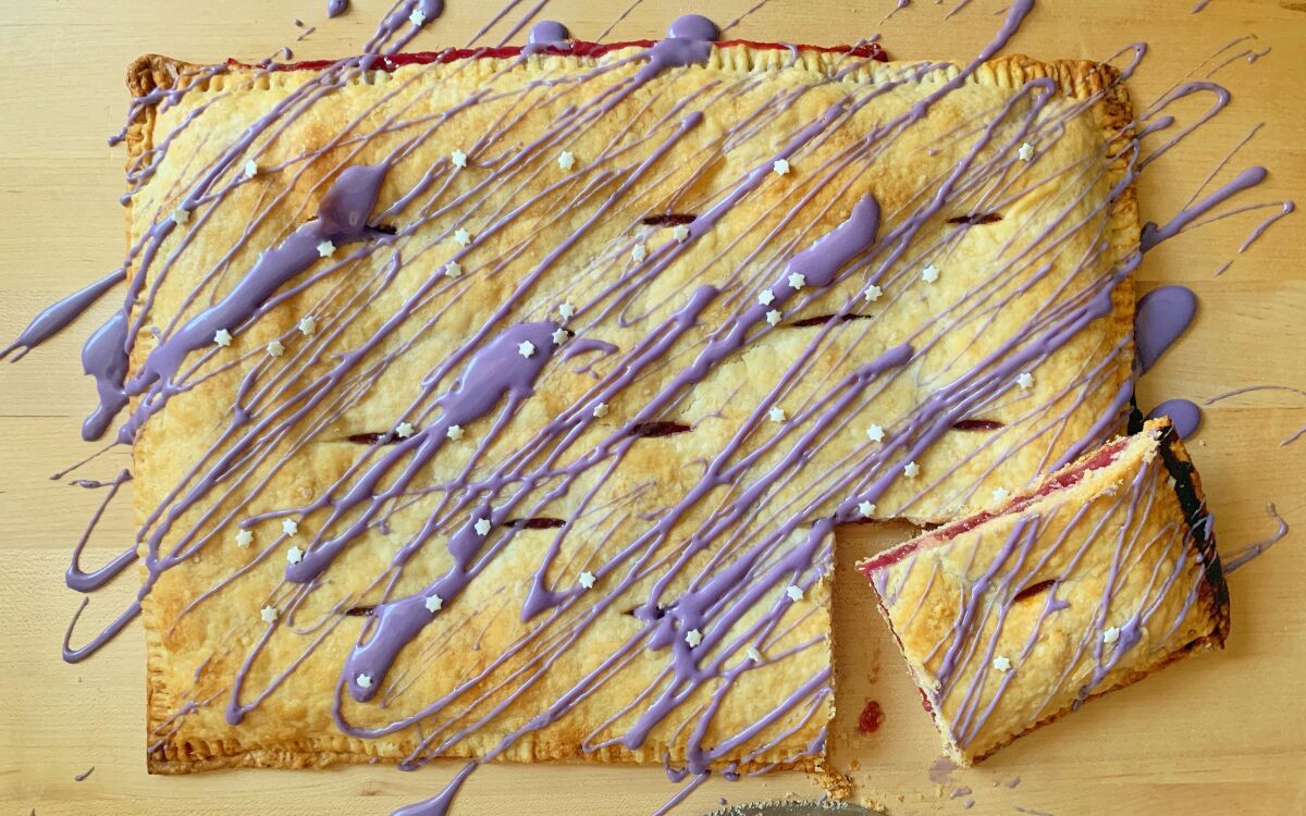 A pastry with purple frosting drizzled over it 