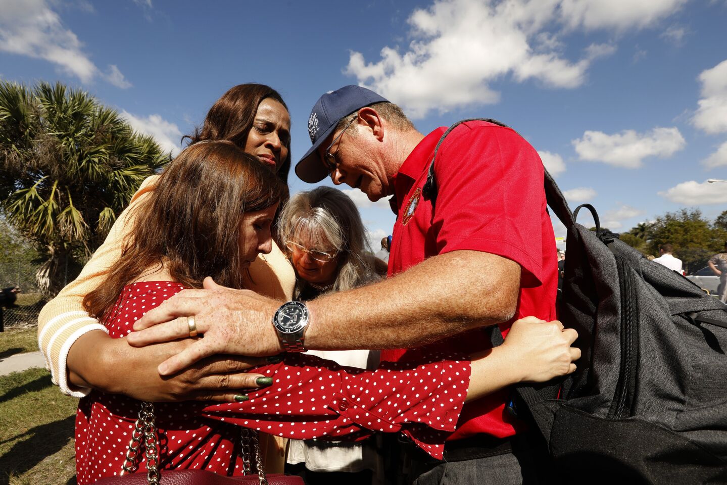 Broward County school board members Robin Bartleman, left, and Rosalind Osgood, second from left, and Chaplain Robert Ossler of the City of Cape Coral Fire/Emergency Department, pray for the victims of the mass shooting after a news conference.