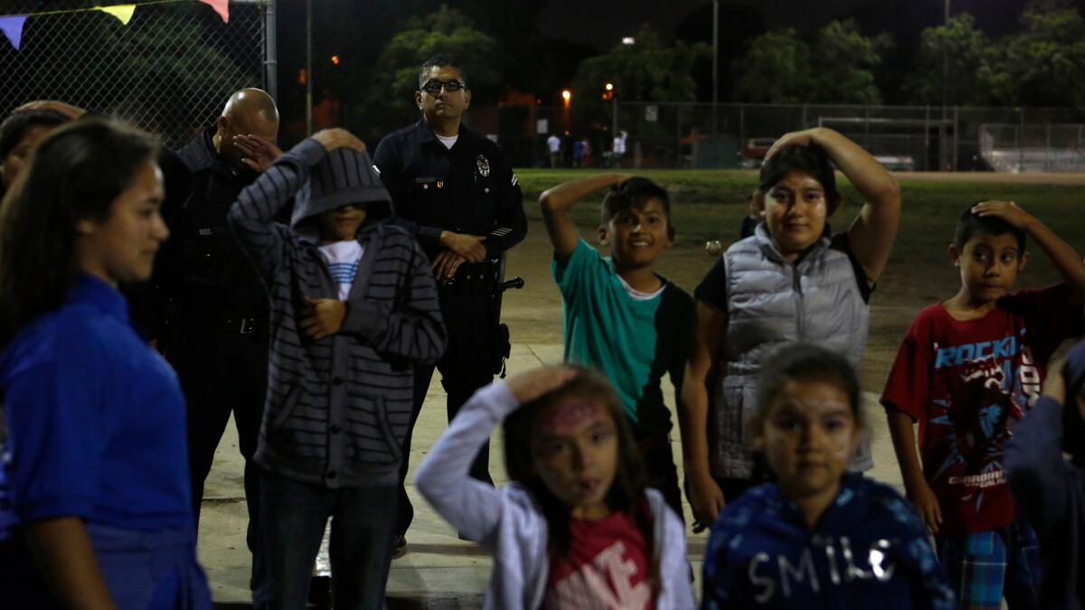 LAPD Officer Roger Medina watches as kids play during the Summer Night Lights program at the Costello Recreation Center in Boyle Heights.