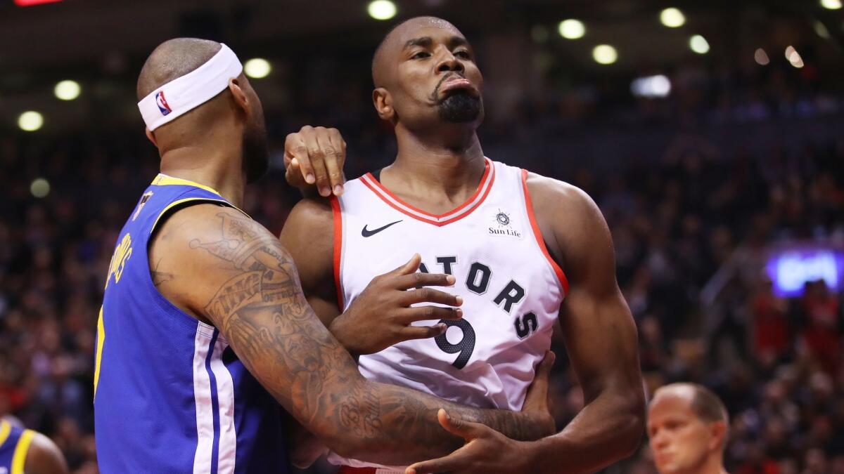 Toronto Raptors' Serge Ibaka (9) is fouled by Golden State Warriors' DeMarcus Cousins (0) in the fourth quarter during Game 1 of the NBA Finals on Thursday.