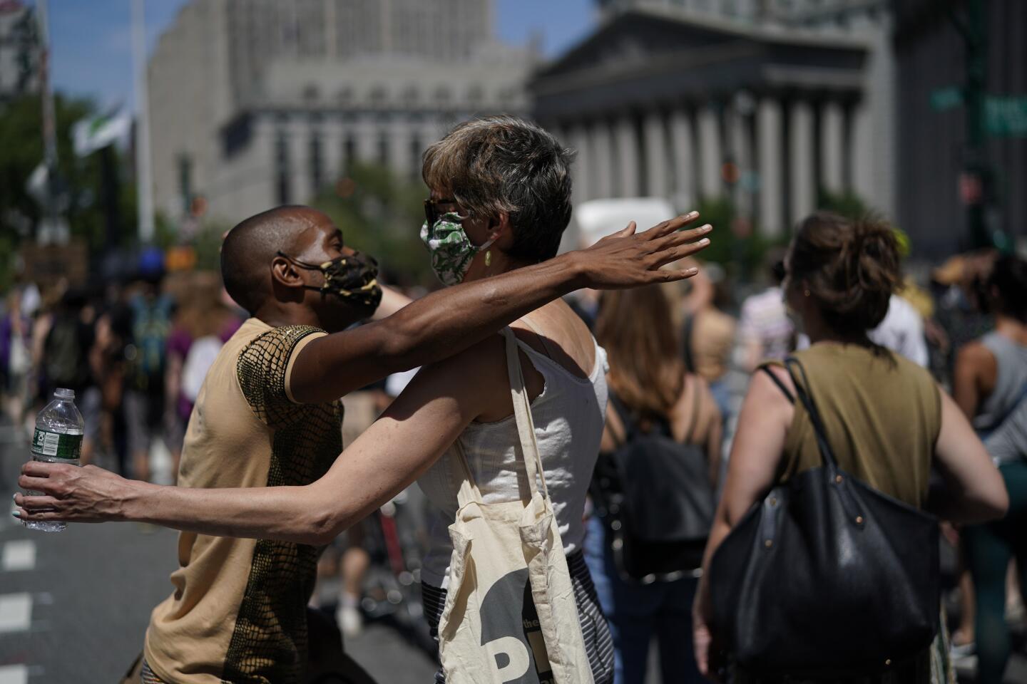 A man giving free hugs, left, embraces a protester at Foley Square during a Juneteenth rally in New York.