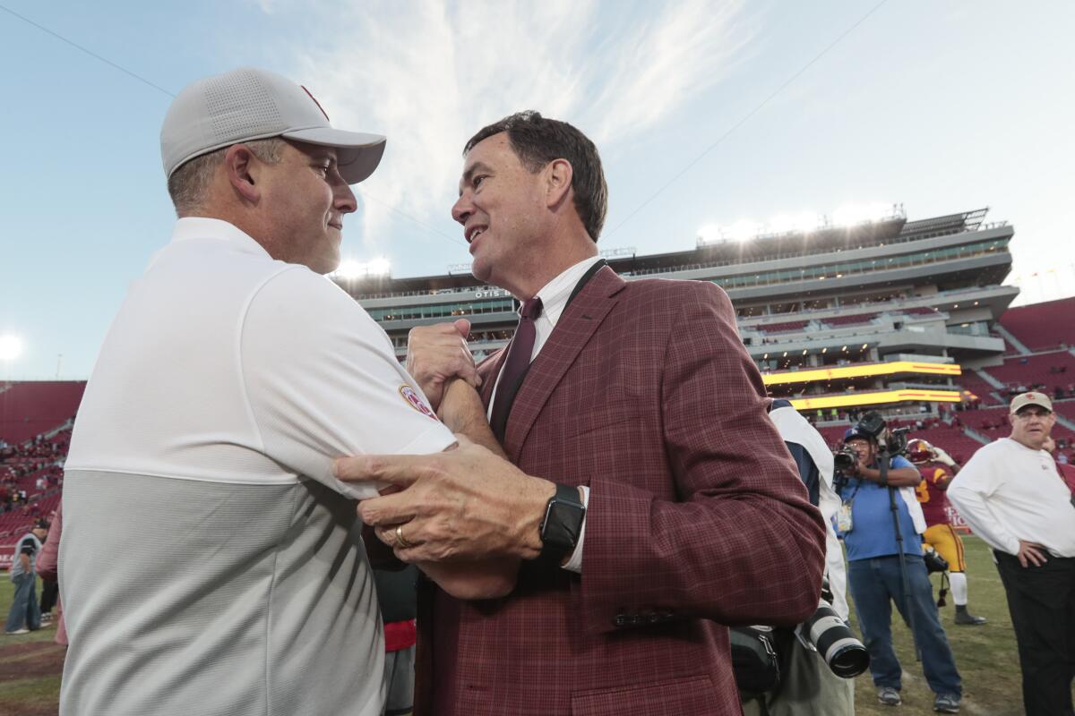 USC head coach Clay Helton is congratulated by Athletic Director Mike Bohn at midfield after a 52-35 win over UCLA at the Coliseum on Nov. 23, 2019.