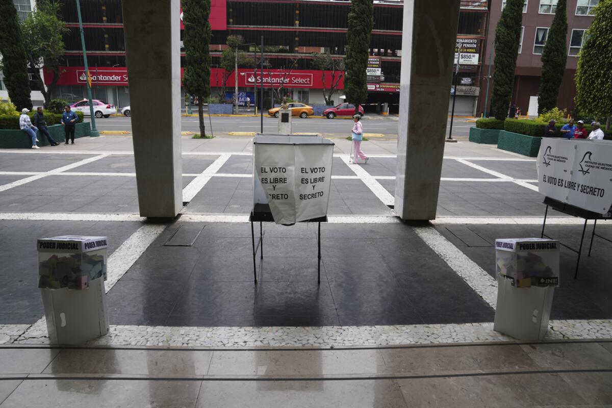 Una mujer pasa por detras de varias urnas