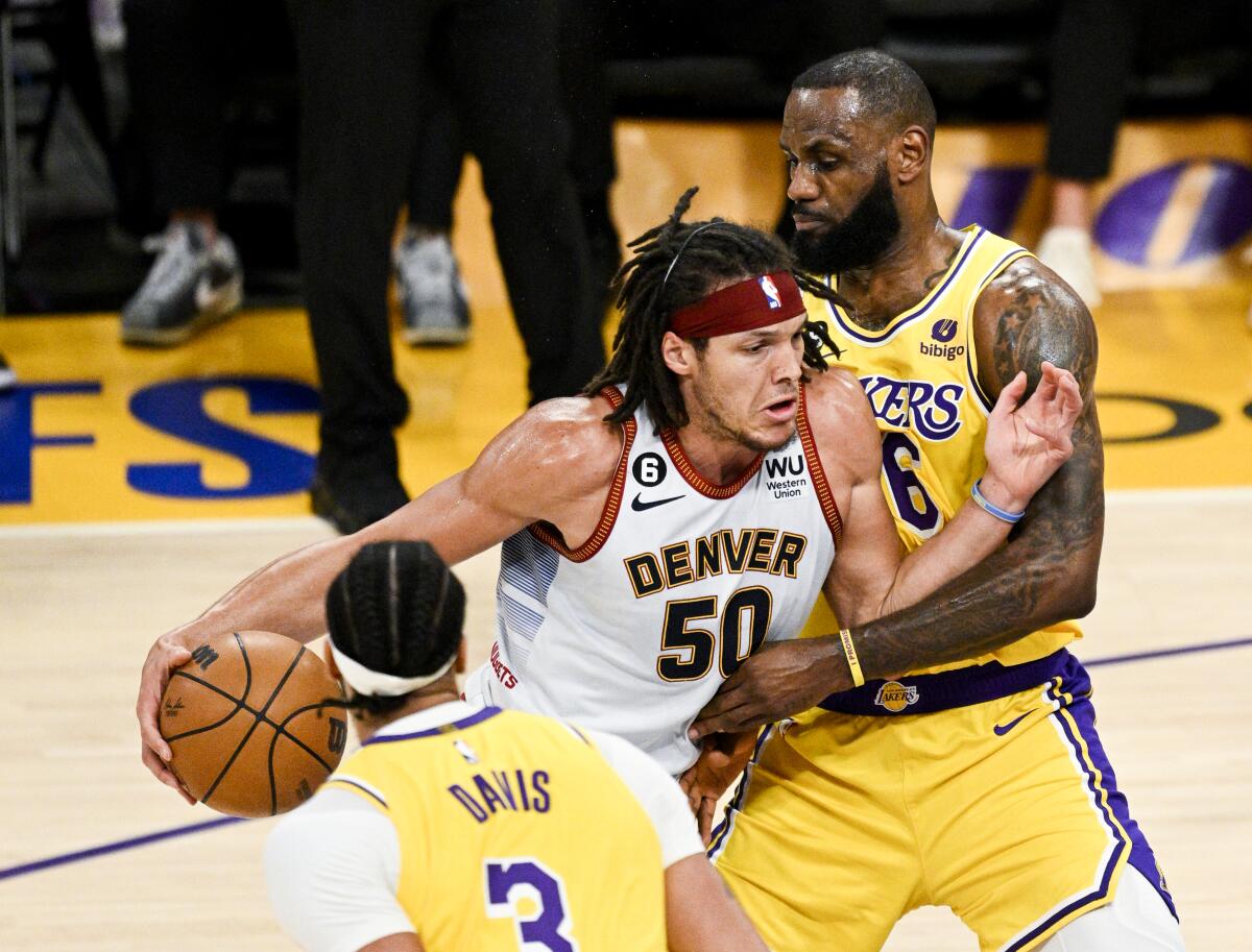 Lakers forward LeBron James, right, tries to cut off a drive by Nuggets forward Aaron Gordon.