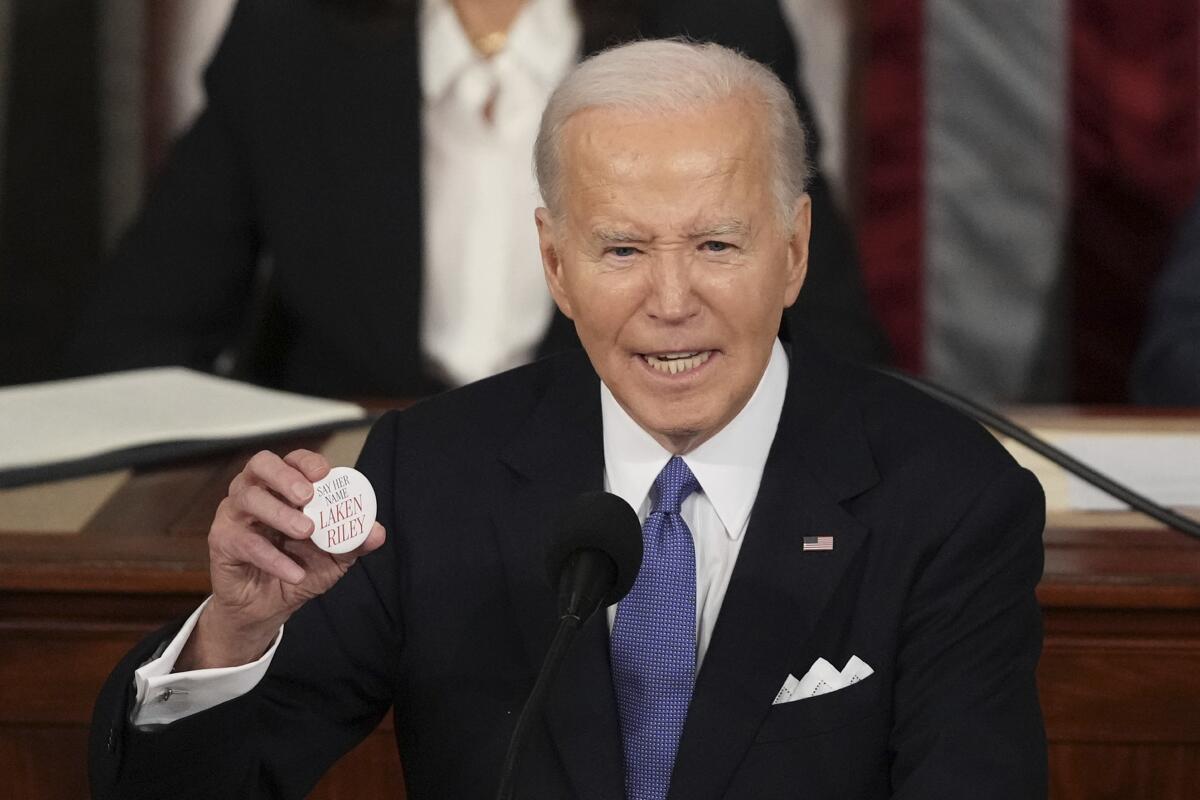 El presidente Joe Biden sostiene un botón de Laken Riley mientras