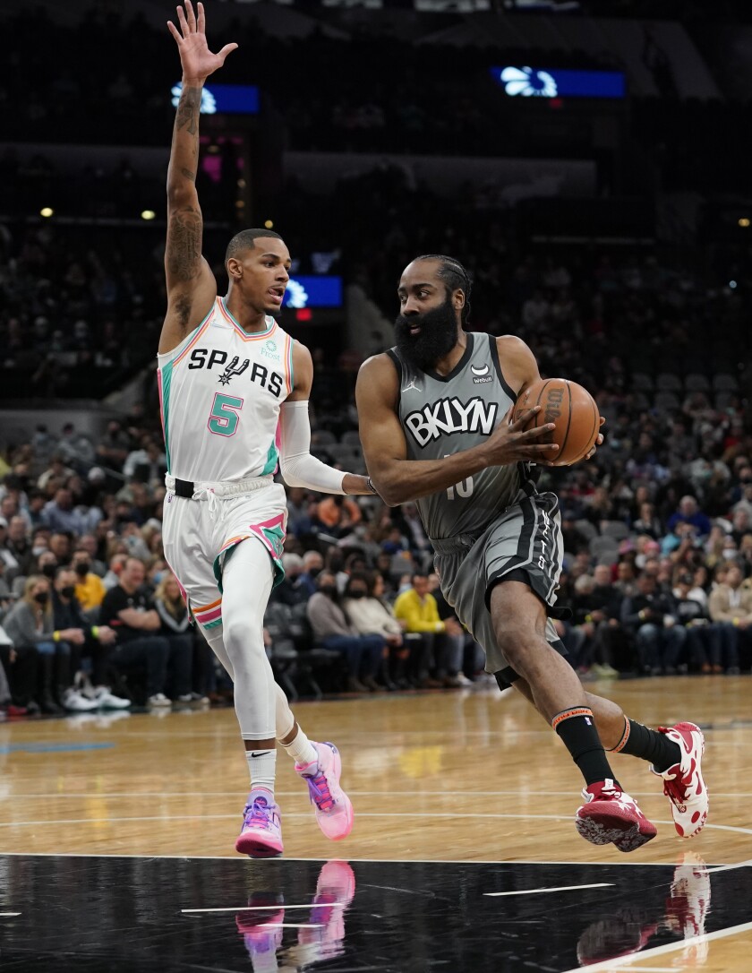 James Harden (13), de los Nets de Brooklyn, intenta avanzar frente a Dejounte Murray (5), de los Spurs de San Antonio, en la primera mitad del partido de al NBA en San Antonio, el viernes 21 de enero de 2022. (AP Foto/Eric Gay)