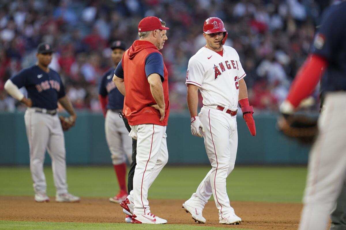 Los Angeles Angels' Mike Trout, center right, is checked out during the third inning of a baseball game against the Boston Red Sox in Anaheim, Calif., Tuesday, June 7, 2022. Trout left the game. (AP Photo/Ashley Landis)