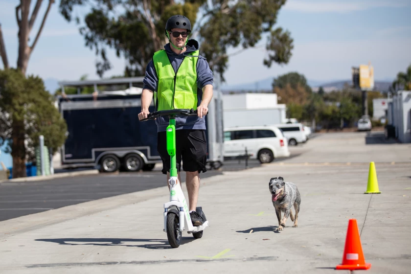 Man on e-scooter with dog beside him
