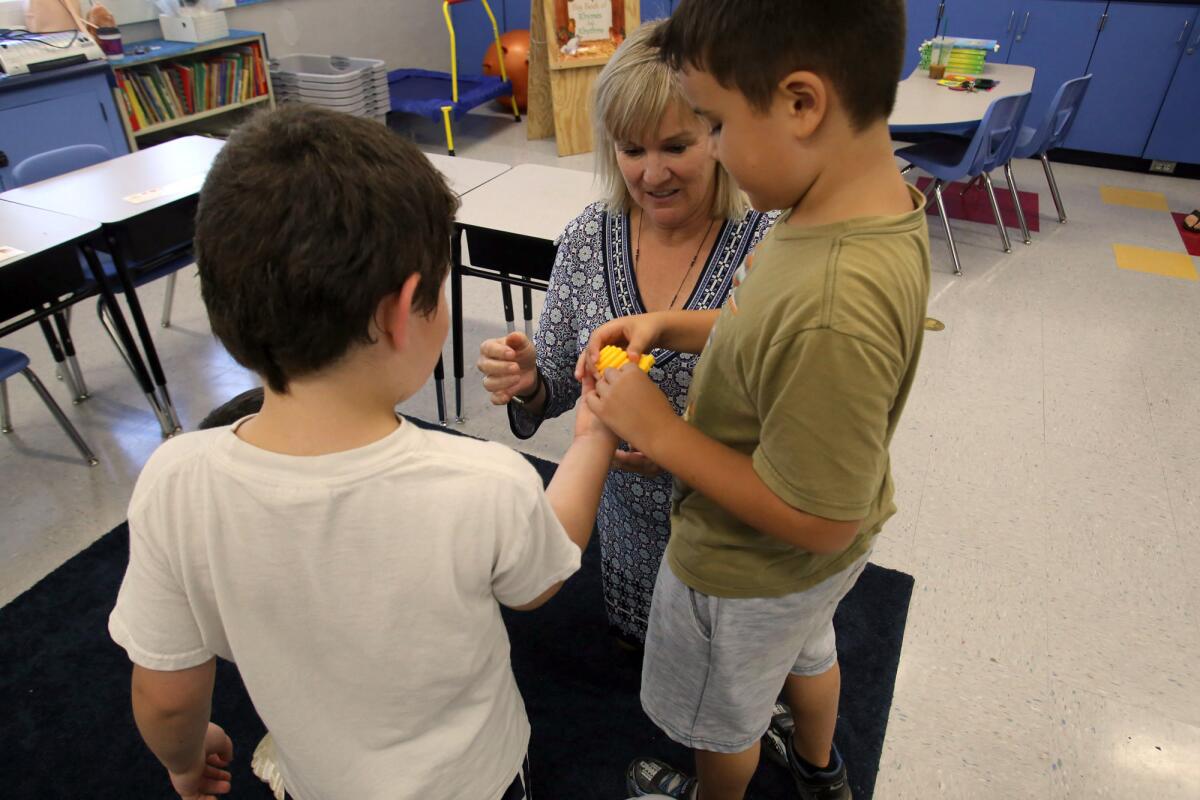 Martha Walter, principal at Bret Harte Elementary School in Burbank, demonstrates with a couple of students how to use a ScrubBee scrubber to wash hands. The school received a donation of ScrubBees from Huntington Beach resident Amy Leinbach for its Language Enriched Autism Program, or LEAP.