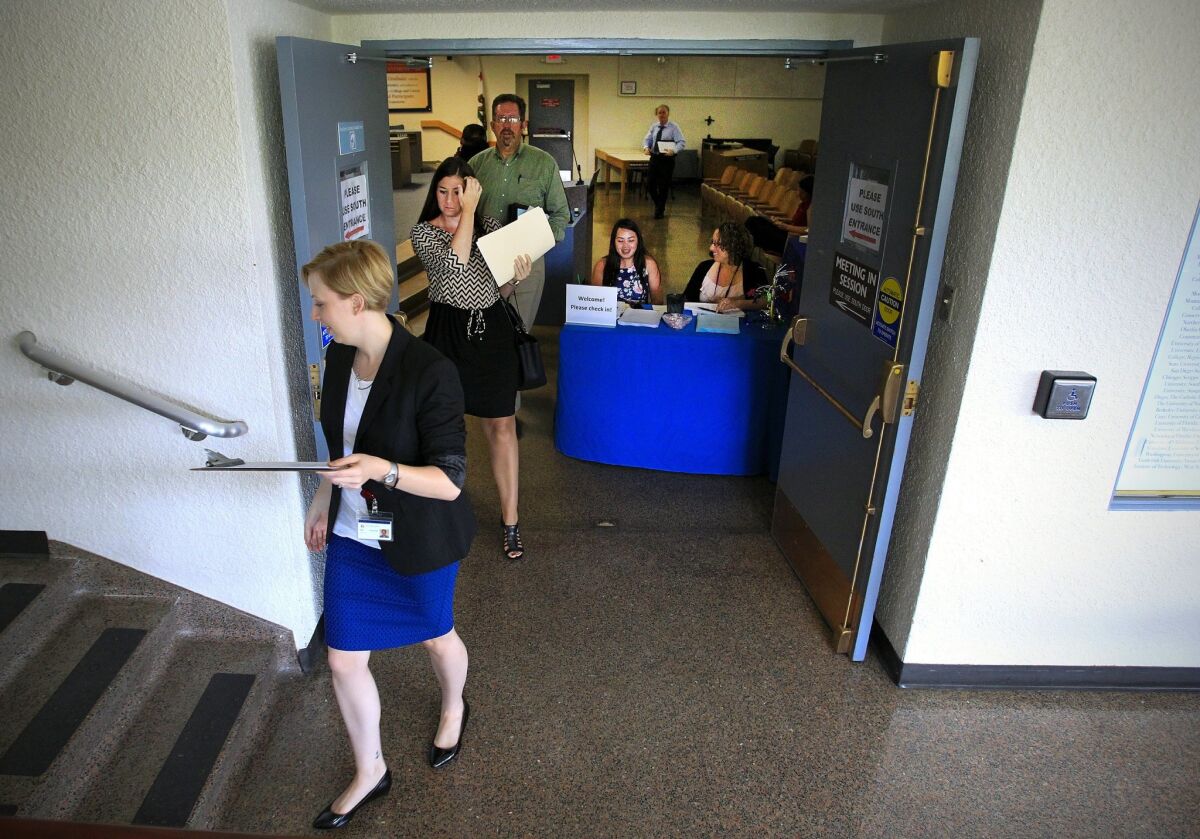 Erin Houston, left, a San Diego Unified School District human resources officer, leads a group of prospective teachers to her office for interviews during a job fair at the district offices.