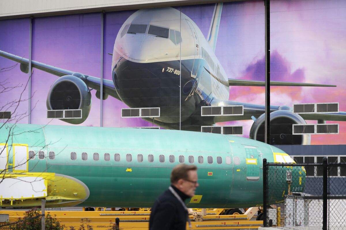 FILE - In this Dec. 16, 2019, file photo a Boeing worker walks past a 737 model fuselage and a giant mural of a jet on the side of the manufacturing building behind in Renton, Wash. On Friday, Feb. 14, 2020, the Federal Reserve reports on U.S. industrial production for January. (AP Photo/Elaine Thompson, File)