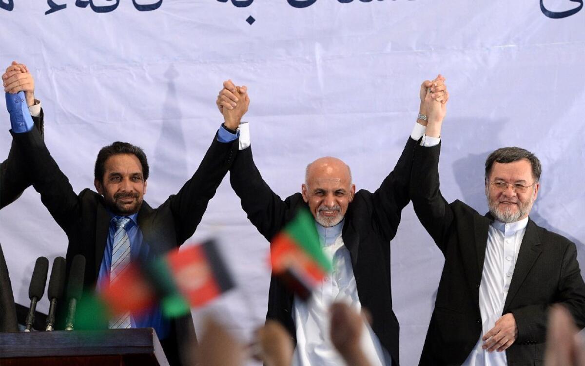 Afghan President-elect Ashraf Ghani Ahmadzai, center, holds hands with his supporters as they gesture to the crowd during a gathering in Kabul on Monday.
