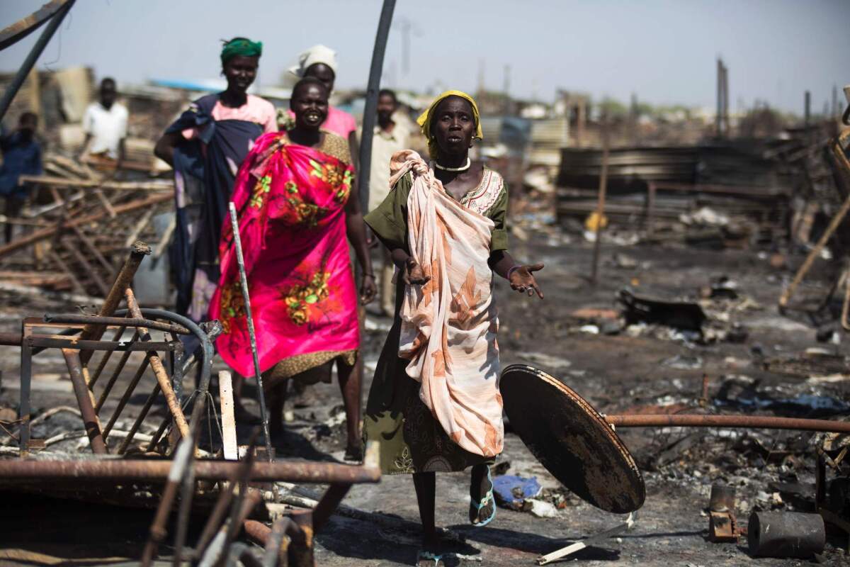 Displaced women residing in the United Nations Protection of Civilians site in Malakal, South Sudan, examine a burnt and looted area, searching for their belongings on Feb. 26.