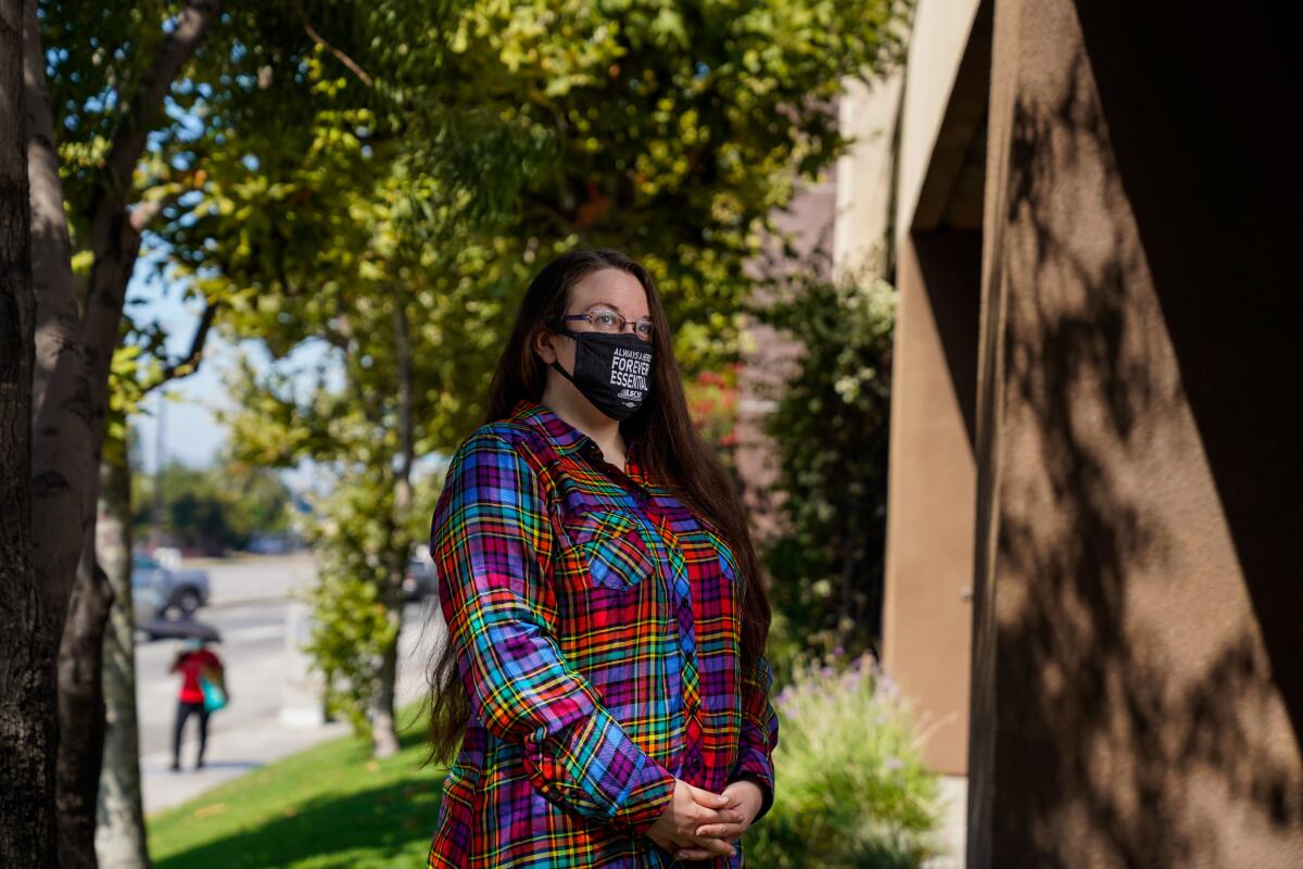 Mary Mueller-Reiche, a cashier at a Ralphs store in Mid-City, poses for a portrait outside while wearing a mask